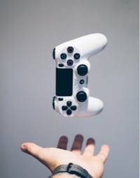 An image of a hand throwing a white playstation controller into the air